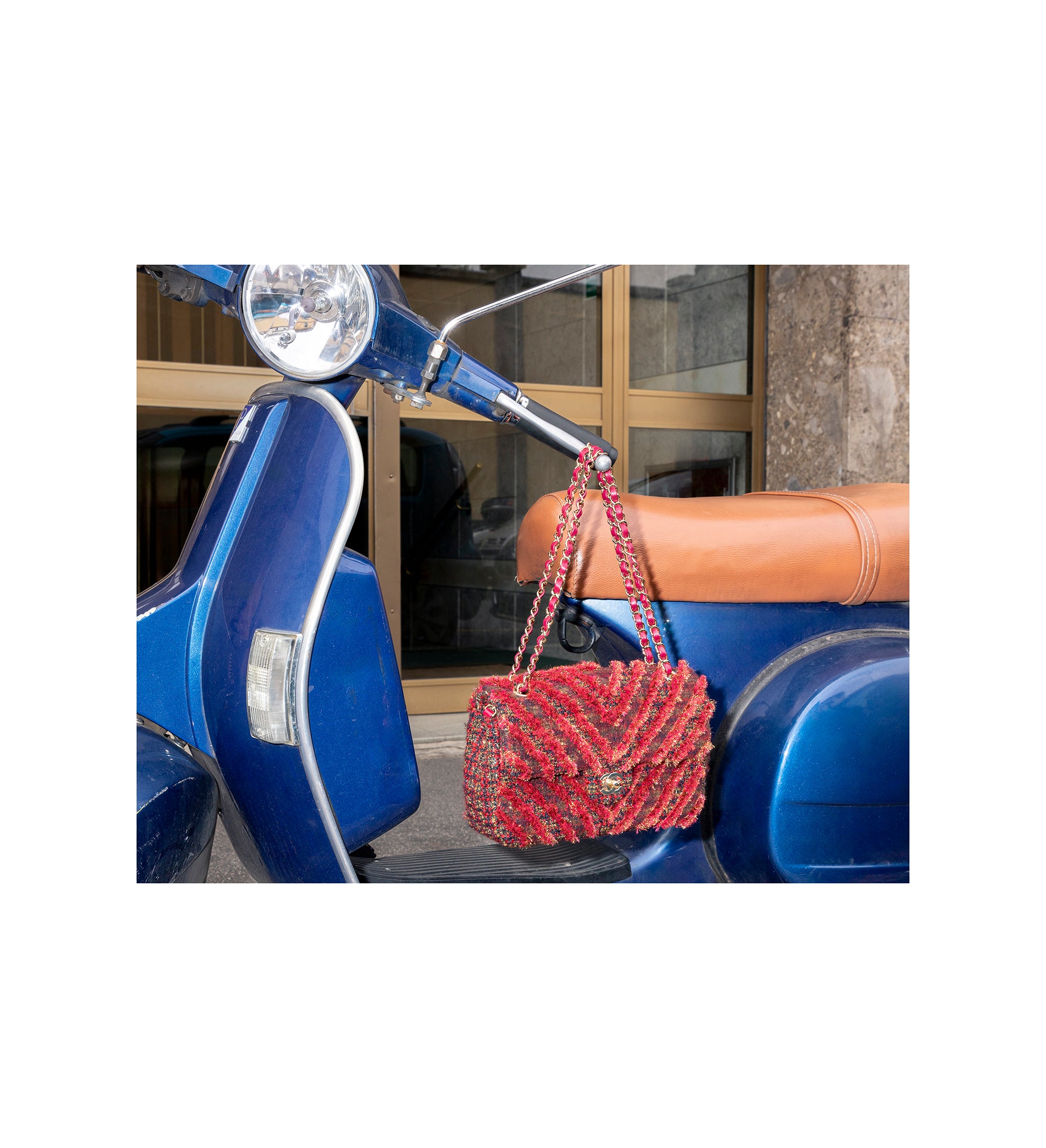 Stylish red patterned handbag hanging on a blue scooter, showcasing a trendy accessory - HerAge.