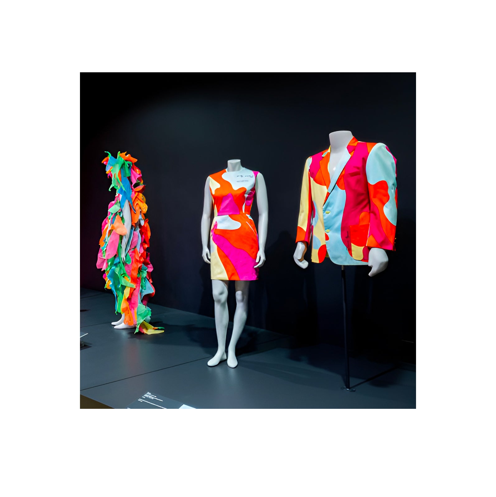 Colorful fashion display featuring vibrant dresses and a suit on mannequins - HerAge